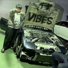 two men standing next to a car with its hood open