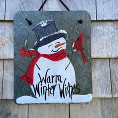 a sign that says warm winter wishes on the side of a building with a snowman painted on it