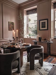 a dining room table set for two with wine glasses, plates and candles on it