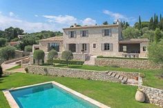 a large house with a swimming pool in front of it and trees around the yard