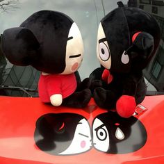 two stuffed animals sitting on the hood of a car with their faces painted black and white