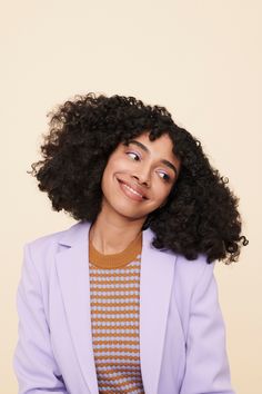 a woman with curly hair wearing a purple jacket