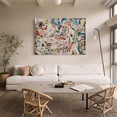 a living room filled with furniture and a painting hanging on the wall above it's windows