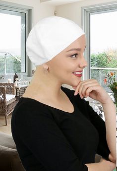 a woman with a towel on her head sitting at a table in front of a window