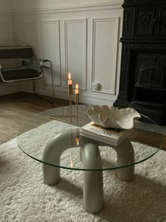 a living room with a glass coffee table and white rugs on the floor in front of a fireplace