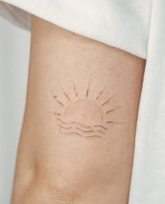 a woman's arm with a sun tattoo on it