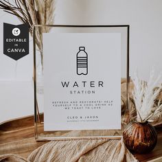 a water station sign sitting on top of a table next to a vase with dry grass