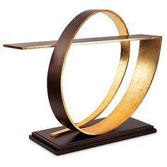 a gold and black sculpture on top of a wooden stand with an oval shaped base