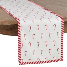 a red and white table runner with candy canes printed on the side, along with a wooden table