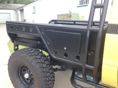 the back end of a black truck parked in front of a white house with an open door