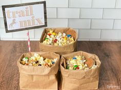 three brown paper bags filled with cereal and marshmallows next to a sign that says trail mix