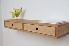 a wooden shelf with two drawers and a bird figurine sitting on top of it