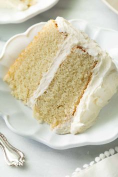 a slice of cake on a white plate with a fork next to it and another piece in the background