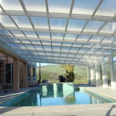 an indoor swimming pool in the middle of a house with glass walls and doors on both sides