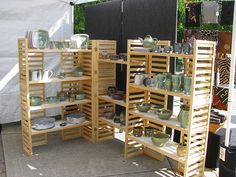 several wooden shelvings stacked on top of each other in front of a white tent