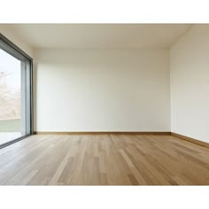 an empty room with wood floors and large window overlooking the trees outside in front of it