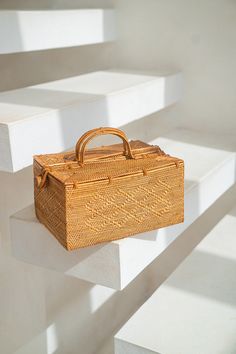 a wicker box sitting on top of white steps next to a handbag in the air