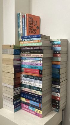 a stack of books sitting on top of a white shelf