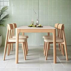 a dining table with four chairs and a potted plant in the corner next to it