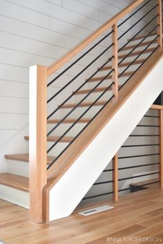 a wooden stair case next to a white wall