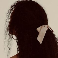 a woman with curly hair wearing a white bow in her back's side view