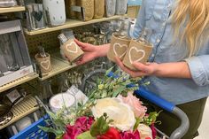 two women holding jars with hearts on them and flowers in the basket next to each other