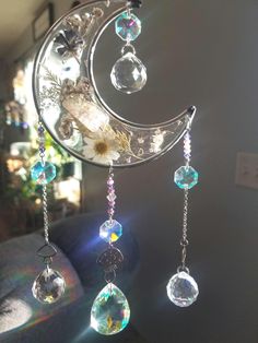 the sun is shining brightly in front of a moon mobile with crystals hanging from it's sides