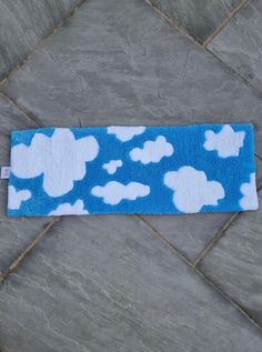 a blue and white towel with clouds on it sitting on a tile floor in front of a wall