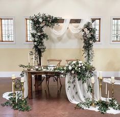 a table with white flowers and greenery is set up for an outdoor wedding ceremony