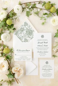 the wedding stationery is surrounded by flowers and greenery, including an apple tree