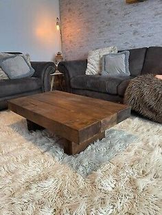 a living room with two couches, a coffee table and pillows on the floor