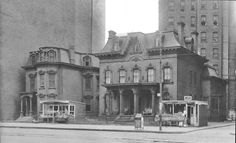 an old black and white photo of a building with two trolleys parked in front of it