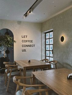 an empty restaurant with wooden tables and chairs in front of a window that says let coffee connect us