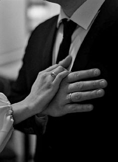 a man and woman holding hands while wearing wedding rings