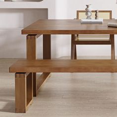 a wooden table with two benches next to it on the floor in front of a white wall