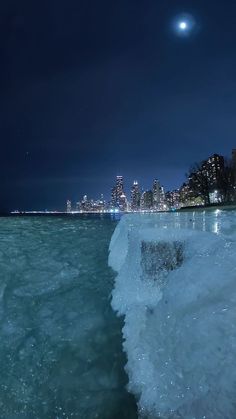 the city skyline is lit up at night as ice drifts across the water in front of it