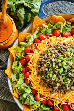 a salad with cheese, lettuce and tomatoes in a bowl next to dressing