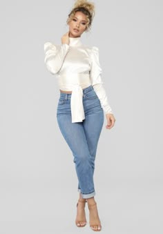 a woman in jeans and a white top posing for the camera with her hands on her hips