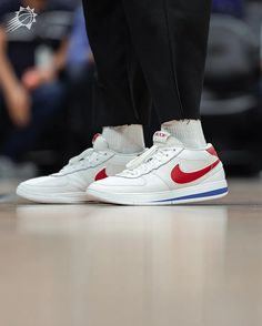 the feet of a basketball player wearing white and red sneakers