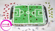 a cake decorated with green frosting and soccer field on top of a table next to confetti sprinkles