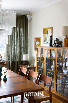 a dining room table and chairs in front of a large window with curtains on it