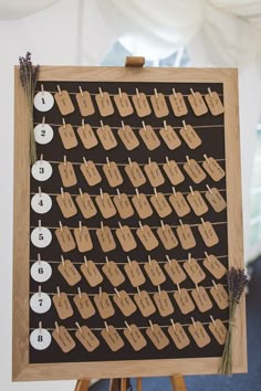 a wooden easel holding a board with clothes pins on it and numbers hanging from the pegs