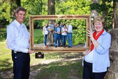 two people standing next to each other in front of a picture frame with an image on it