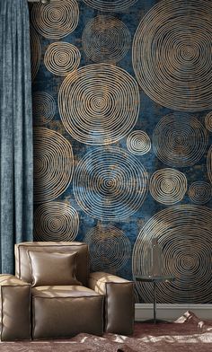 a chair and ottoman in front of a blue wallpaper with gold circles on it