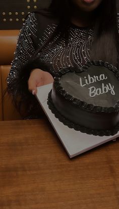 a woman sitting at a table in front of a book with a cake on it