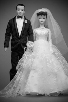 two dolls dressed in wedding attire standing next to each other