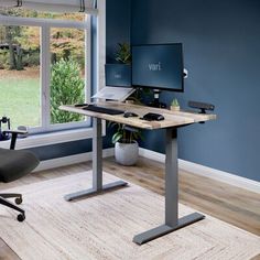 a computer desk with a monitor and keyboard on top of it in front of a window