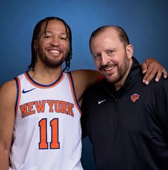 two men standing next to each other in front of a blue background