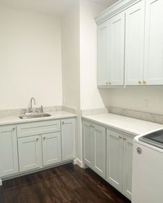 an empty kitchen with white cabinets and wood floors