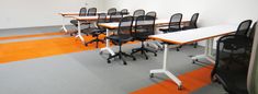 an empty room with chairs and desks in the middle, on top of carpeted flooring